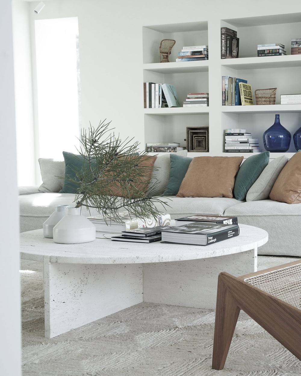 Modern living room with a white sofa, wooden chair, and bookshelf.