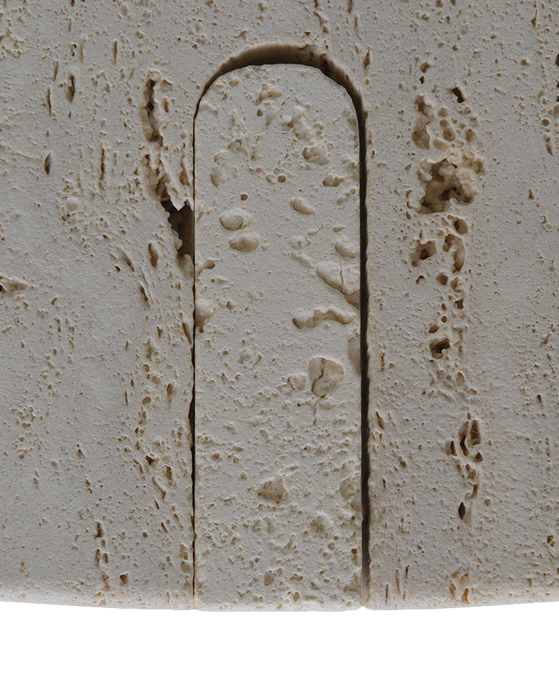 Close-up of a textured stone surface with an arch-shaped groove.