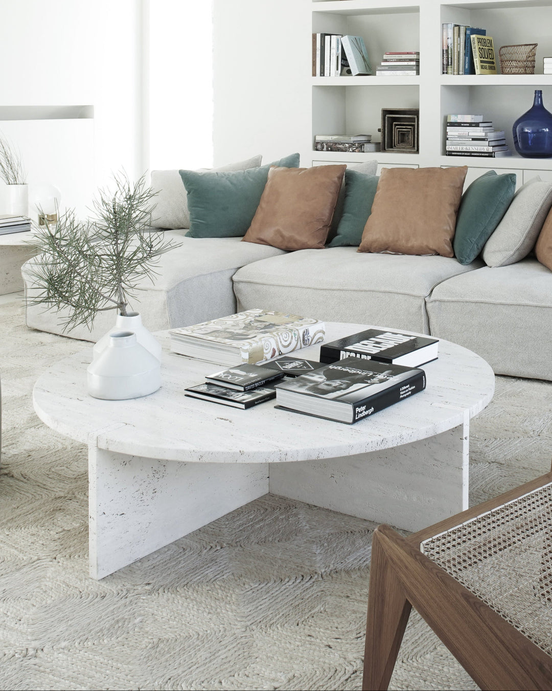 Modern living room with white sofa, bookshelf, and wooden chairs.