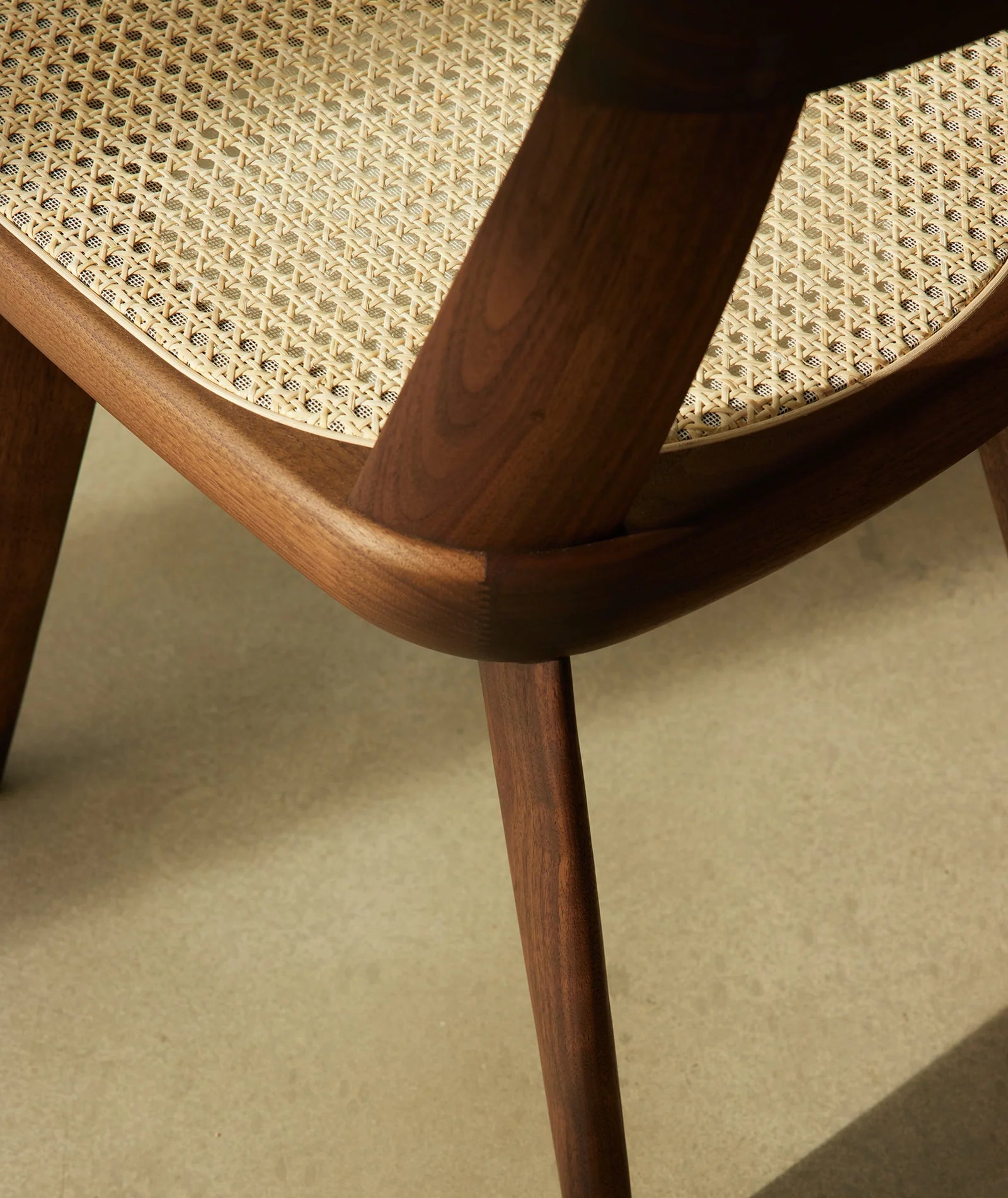 Close-up of a wooden chair with woven seat on a neutral background