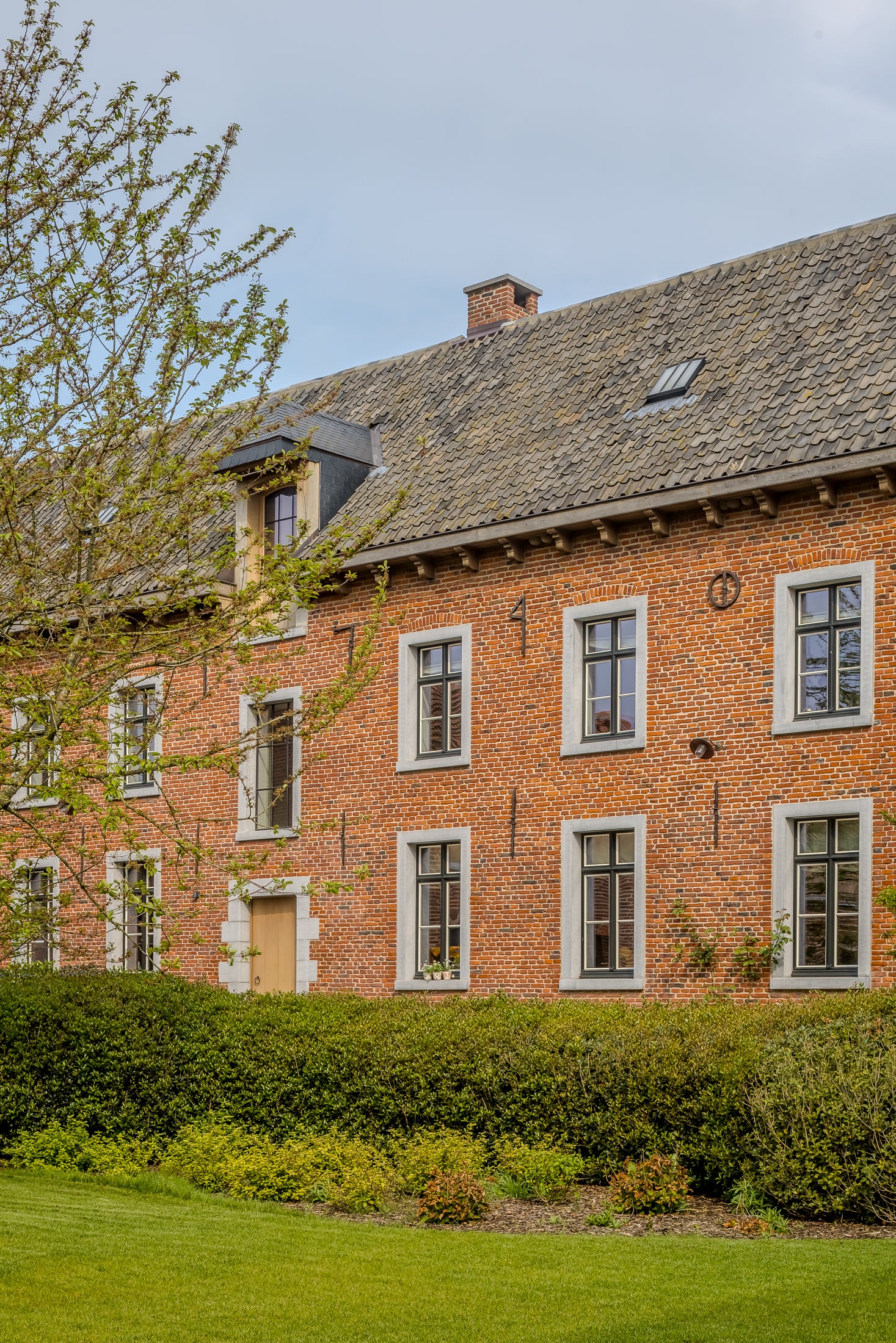 Brick building with greenery in front on a clear day