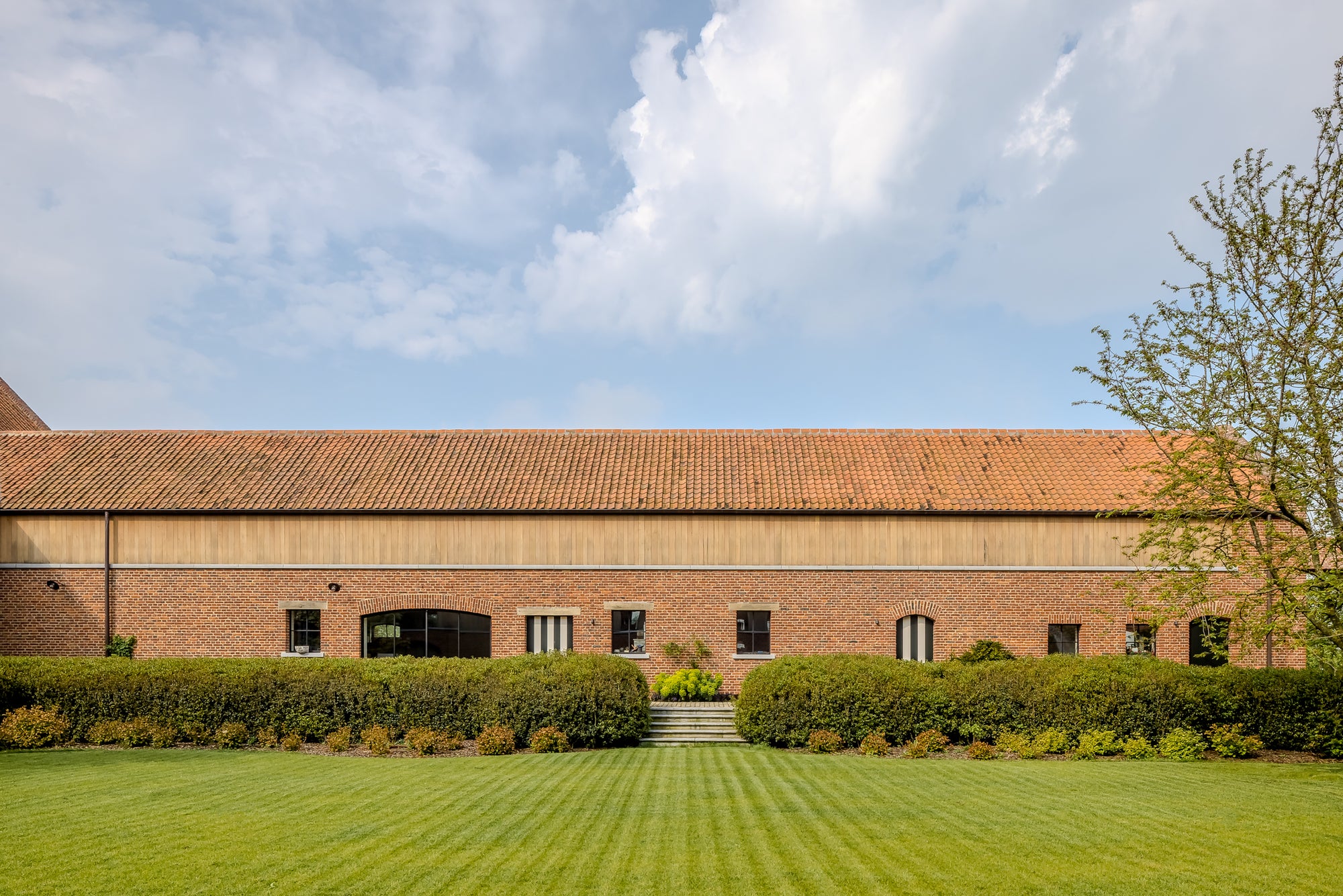 Brick building with a red roof and green lawn under a blue sky