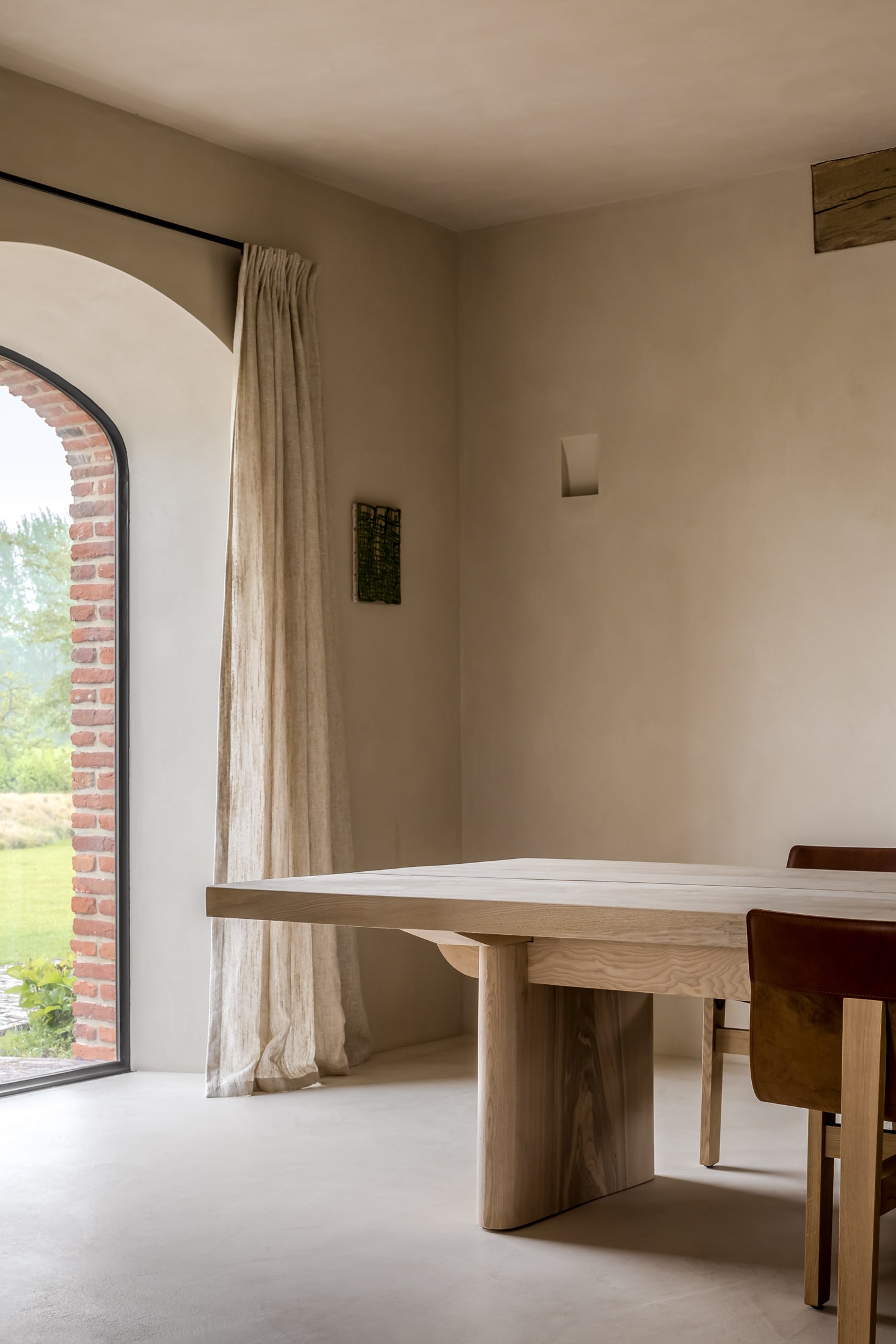 Modern interior with a wooden dining table and chairs near a large window with a view of greenery.