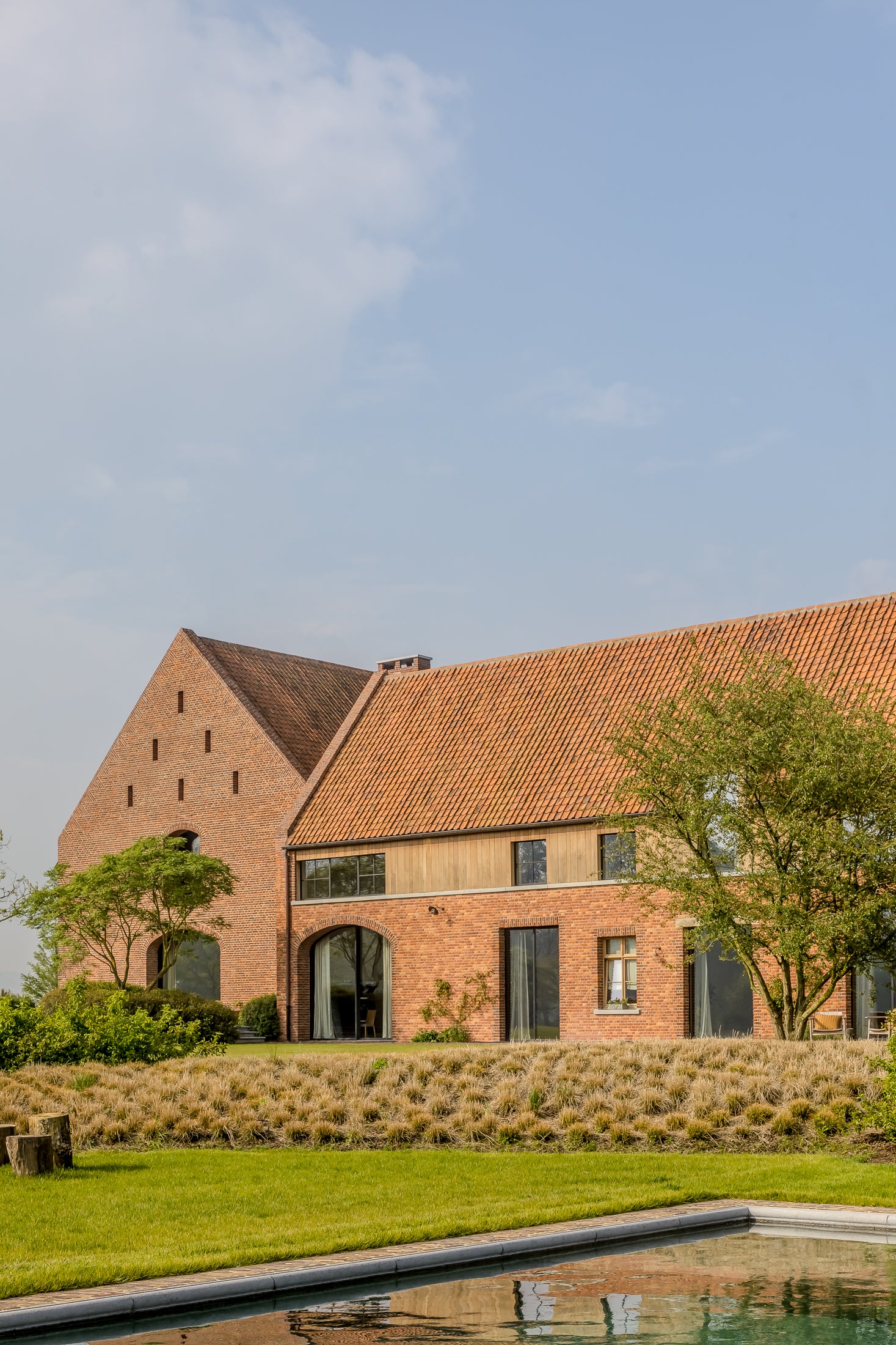 Brick building with a pool and garden under a clear blue sky