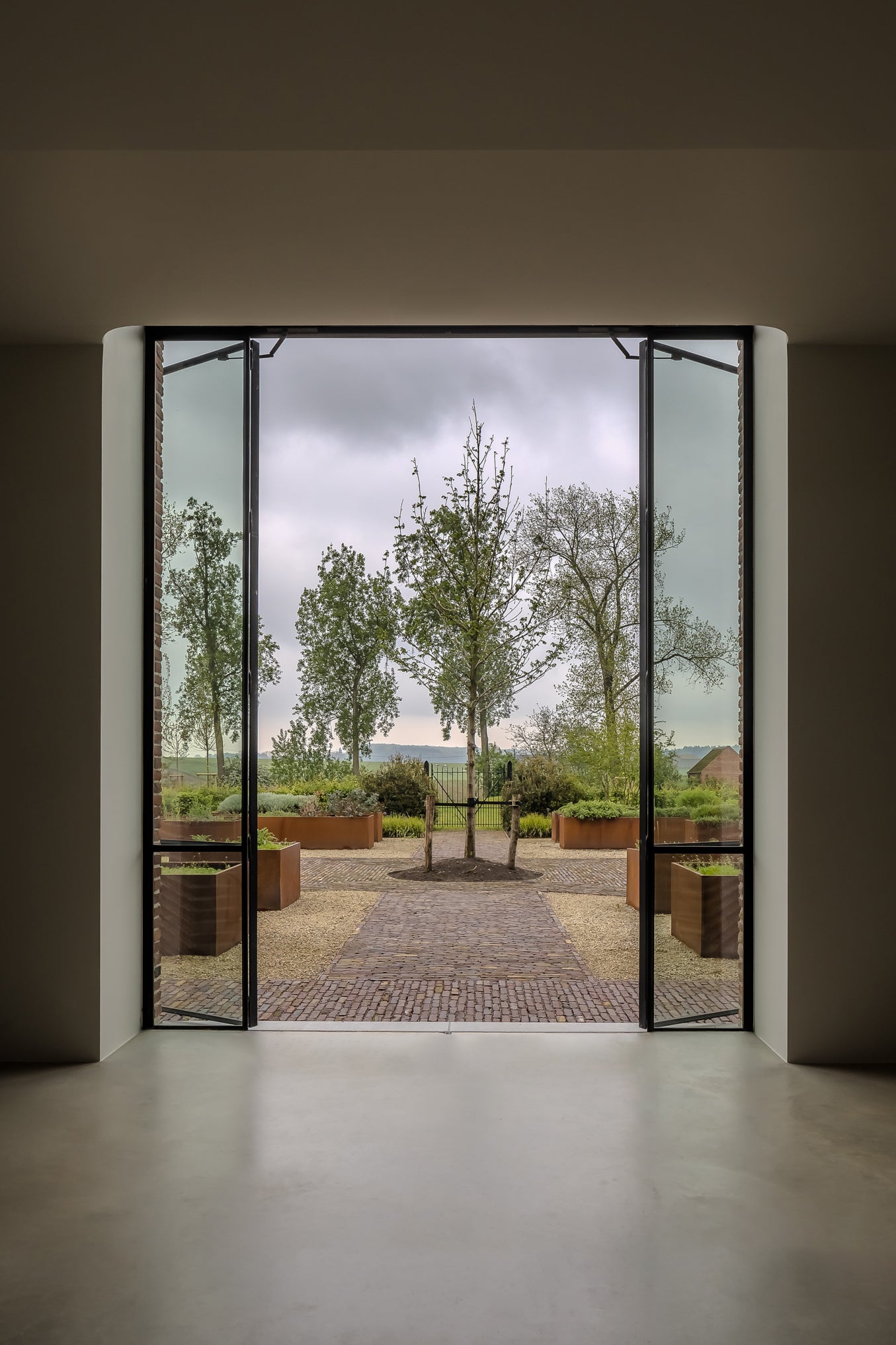 Large glass door opening to a garden with trees and a path.
