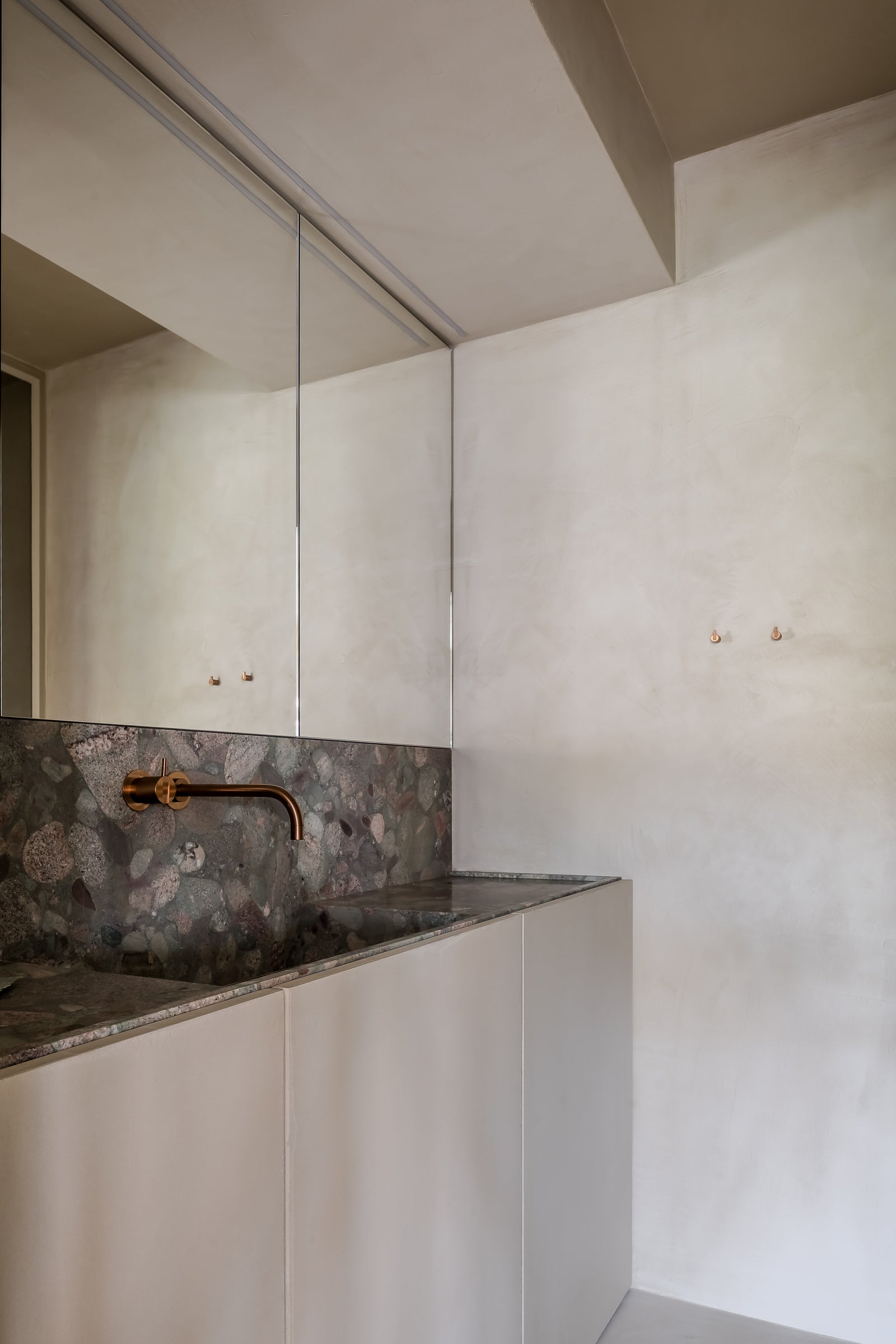 Modern bathroom with white cabinets, marble countertop, and gold faucet.