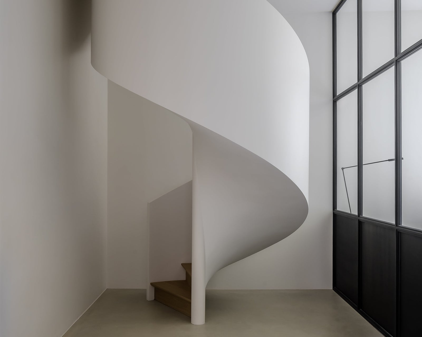 Spiral staircase in a modern interior setting with a large window.